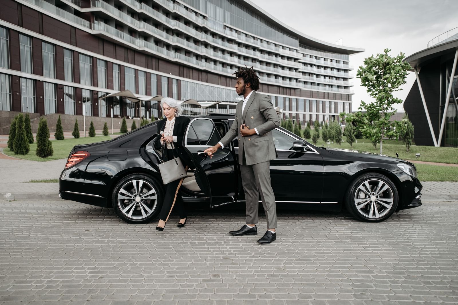 Lux4Rides chauffeur discreetly assisting a VIP client from a black Mercedes sedan