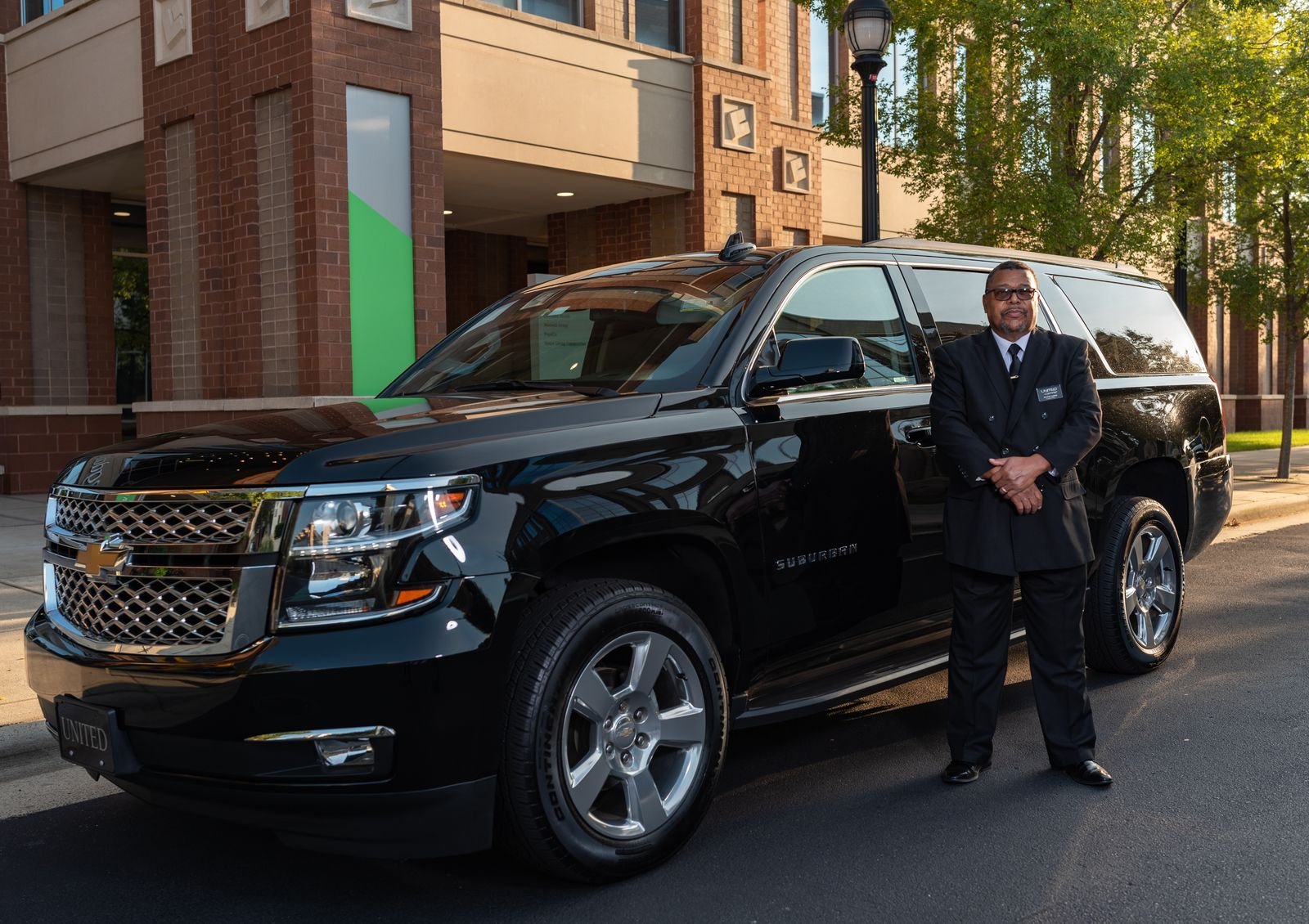 Lux4Rides chauffeur standing beside a gleaming black Chevrolet Suburban for an executive LAX transfer