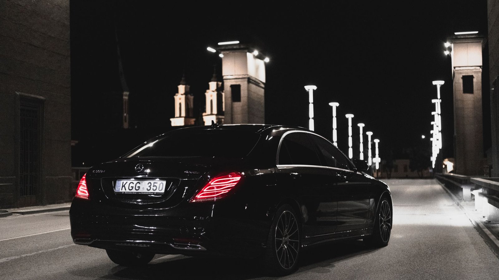 Black luxury sedan parked on a city street at night, ready for a chauffeured World Cup pickup
