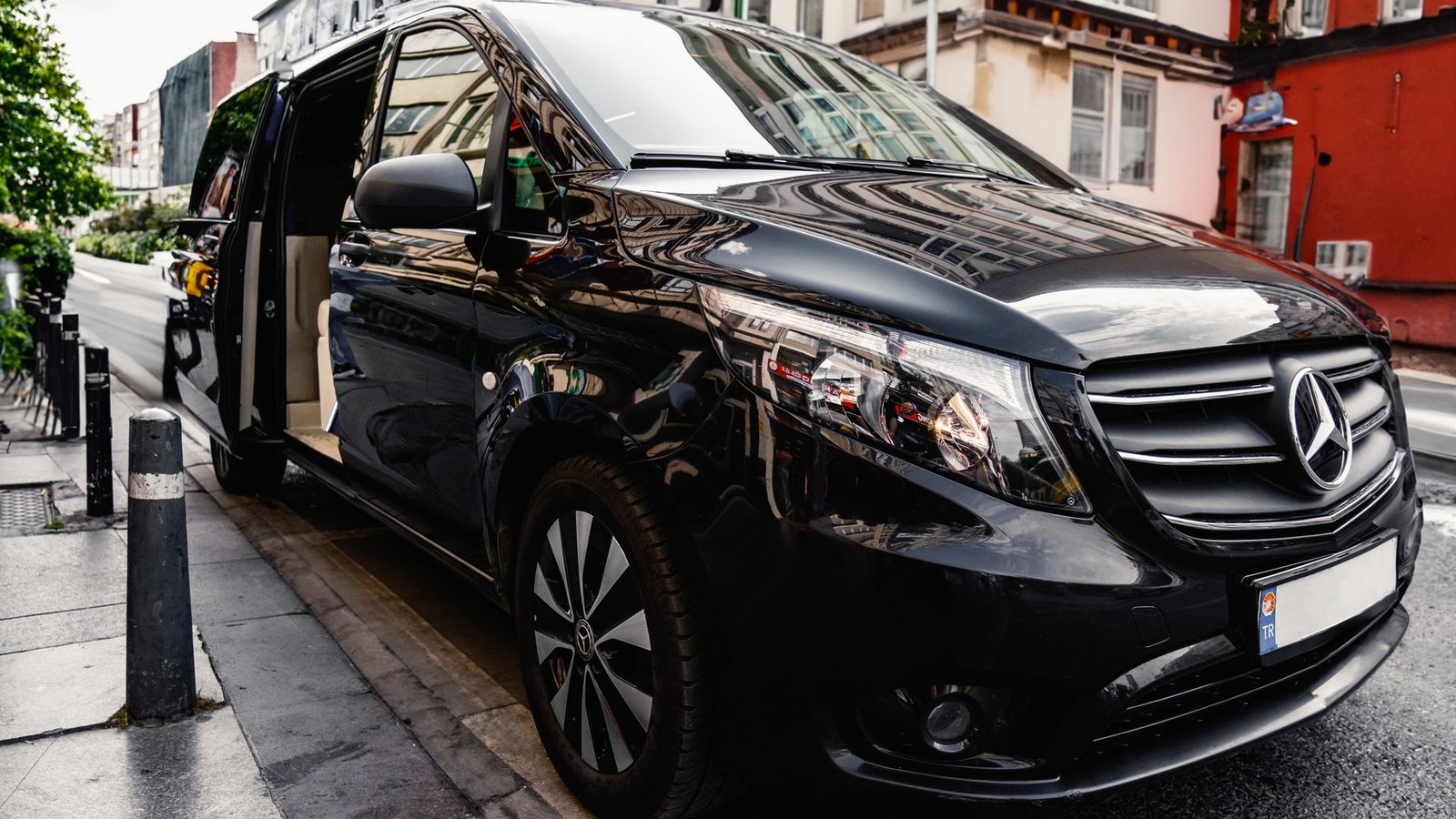 Chauffeur-driven luxury van waiting curbside with the door open for airport pickup