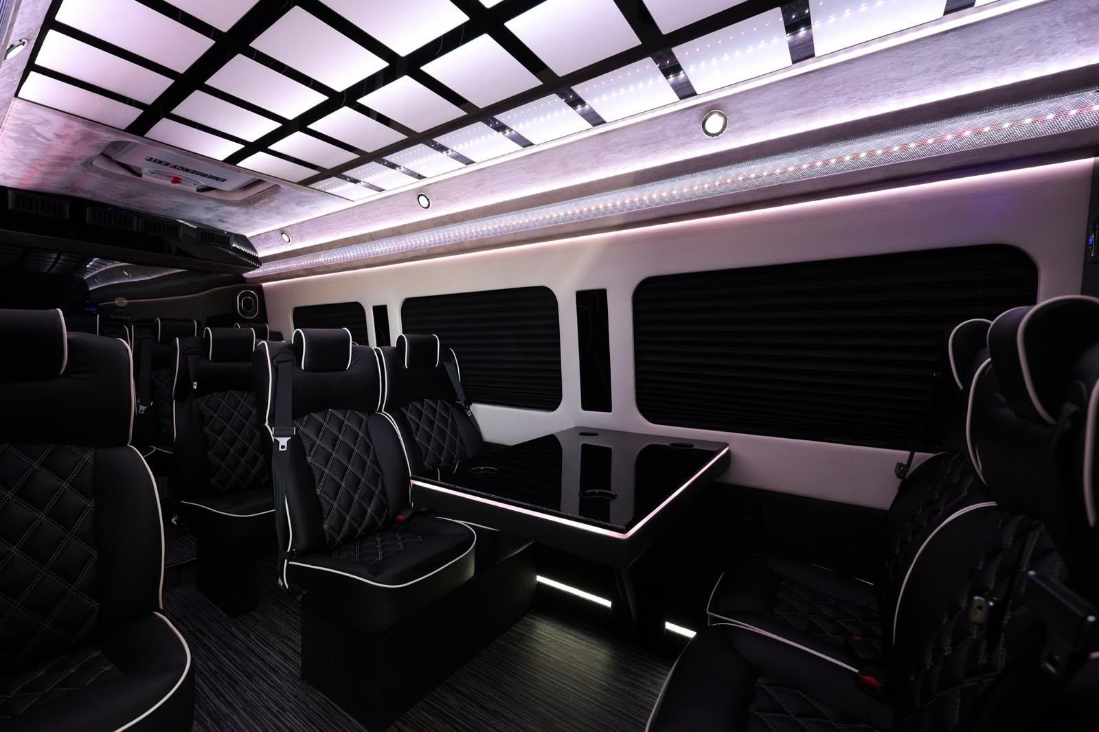 Executive Mercedes-Benz Sprinter cabin with facing leather seats and a conference table, used for production and VIP movements