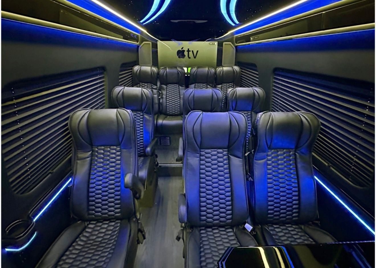 Interior of our executive Mercedes-Benz Sprinter looking toward the front, with quilted leather captain's chairs and a screen